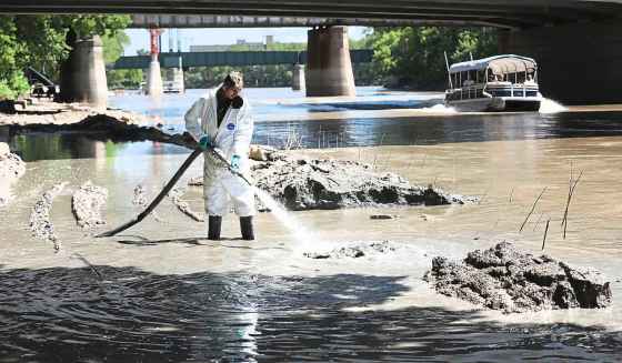 City of Winnipeg worker Nobi Qasi hoses down the walkway along the Assiniboine River west of The Forks. High water levels and repeated rainfall have made it difficult for cleanup crews this summer. (Ruth Bonneville / Winnipeg Free Press)