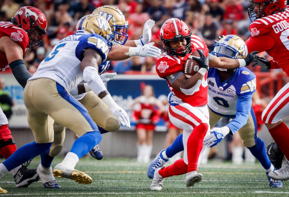 Winnipeg Blue Bombers closes in on Calgary Stampeders running back Peyton Logan, centre, during the first half. (Jeff McIntosh / The Canadian Press)