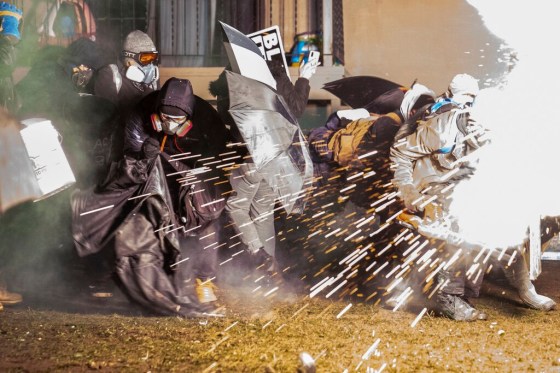 CPDemonstrators take cover from crowd-dispersal munitions fired by police while protesting the shooting death of Daunte Wright in Brooklyn Center, Minn., Tuesday night. (John Minchillo / The Associated Press)