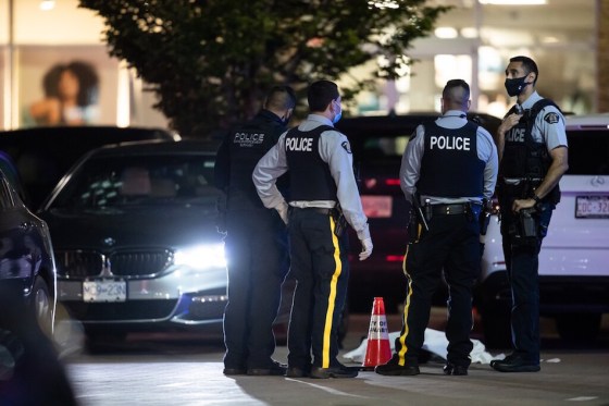 CPRCMP officers beside the body of a shooting victim in Burnaby, B.C., on Thursday. (Darryl Dyck / The Canadian Press)