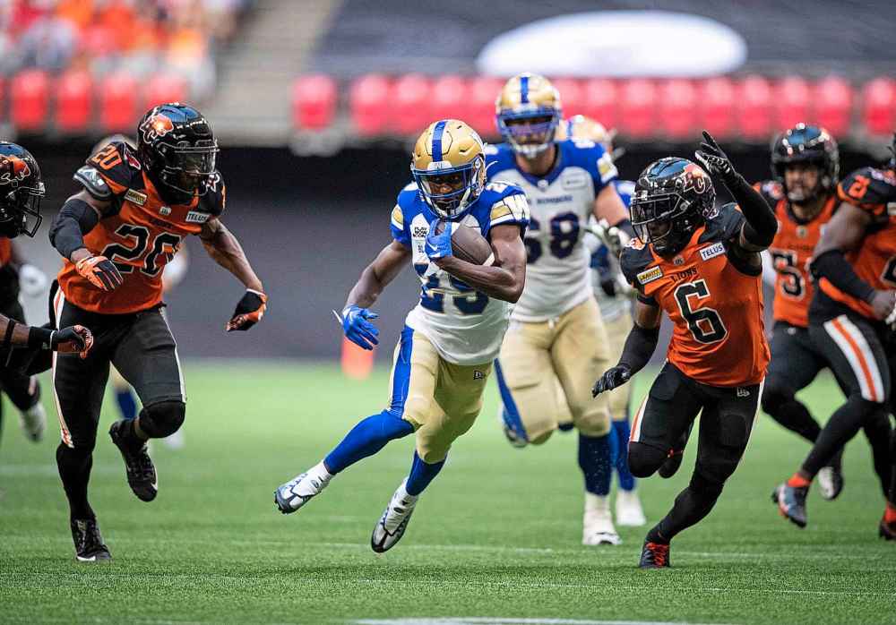 THE CANADIAN PRESS
DARRYL DYCK / THE CANADIAN PRESS
Winnipeg Blue Bombers' Greg McCrae, centre, carries the ball for a first down past B.C. Lions' Boseko Lokombo (20) and T.J. Lee (6) during the first half.