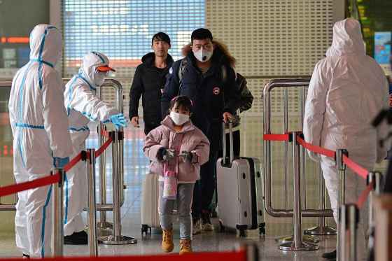 Chinatopix / The Associated PressPeople in protective suits screen travelers at a railway station in Nanjing in eastern China's Jiangsu Province, Tuesday. Hong Kong hospitals cut services as medical workers were striking for a second day Tuesday to demand the border with mainland China be shut completely.