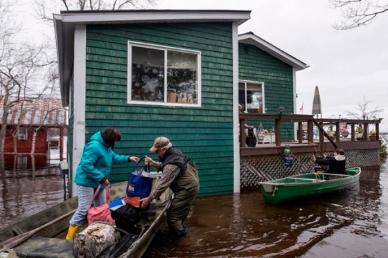 Darren Calabrese / THE CANADIAN PRESSResidents carry groceries and clothes out of canoes as floodwaters surround a home on Grand Lake in New Brunswick on Tuesday.