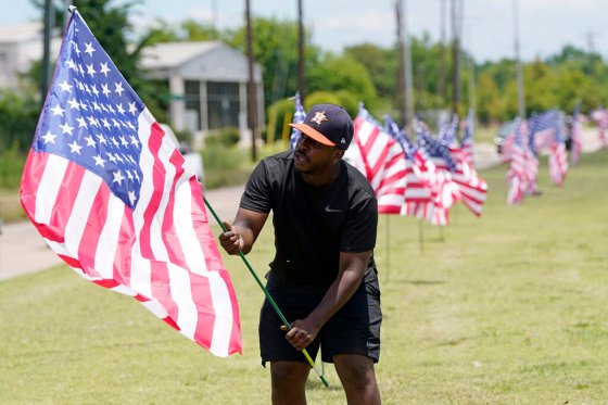 David J. Phillip / The Associated PressBryan Smart plants American flags along Hillcroft Ave. as he walks toward The Fountain of Praise church Sunday, in Houston, Texas.