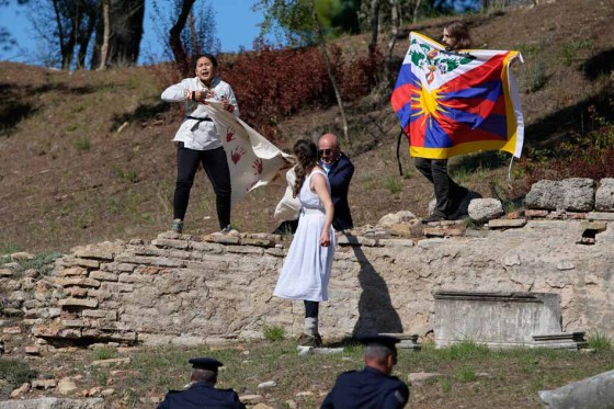 A police officer tries to stop protesters displaying a Tibetan flag and a banner reading