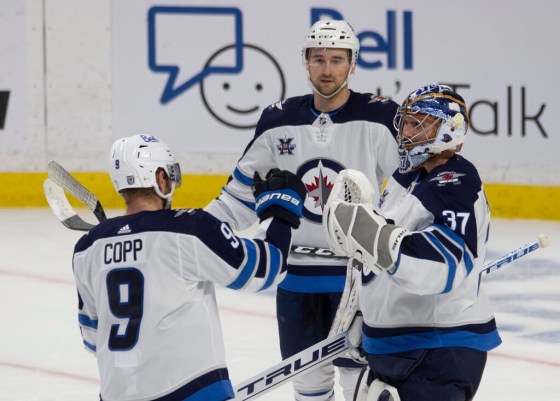 CPAndrew Copp, Neal Pionk and goaltender Connor Hellebuyck celebrate after the Winnipeg Jets beat the Ottawa Senators on Thursday. (Adrian Wyld / The Canadian Press)