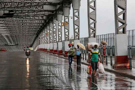 Bikas Das / The Associated PressCommuters walk along the city's iconic landmark, Howrah Bridge to cross the Hooghly River as it rains in Kolkata, India, Wednesday. Amphan, a powerful cyclone, has slammed ashore along the coastline of India and Bangladesh.