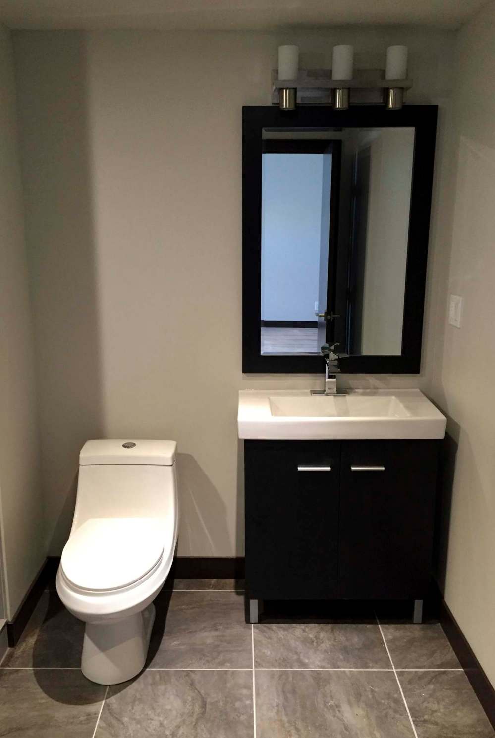 The one-piece toilet and vanity/mirror are set along the far wall as you enter the bathroom.