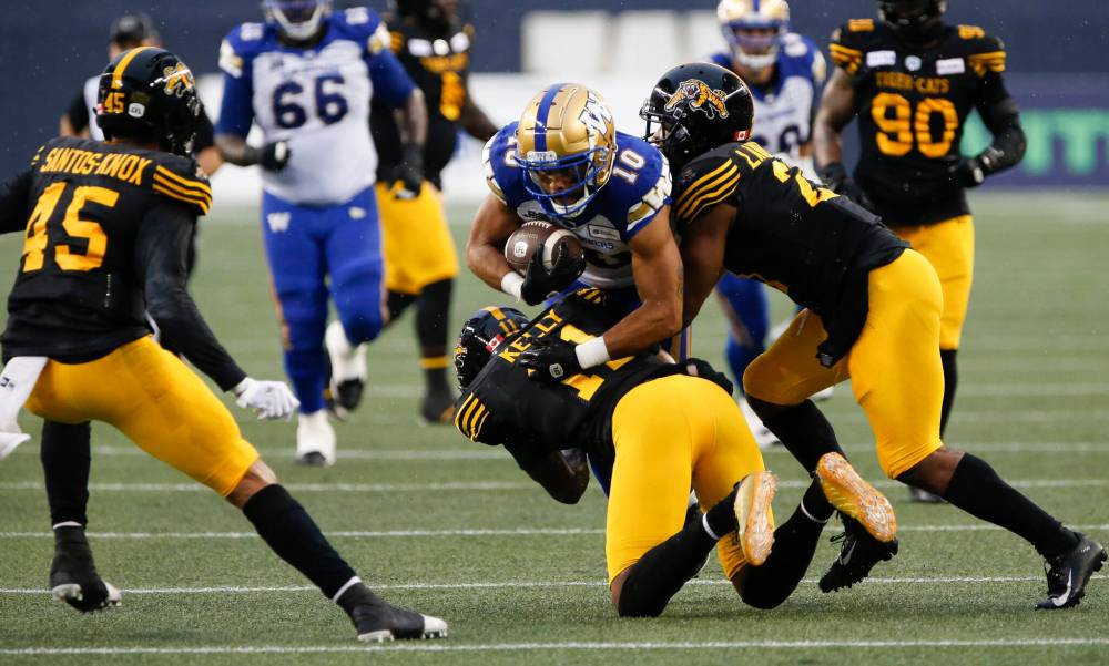 THE CANADIAN PRESS/John Woods
Winnipeg Blue Bombers’ Nic Demski (10) gets tackled by Hamilton Tiger-Cats’ Kameron Kelly (11) and Simoni Lawrence (21) during the first half in Winnipeg, Friday.