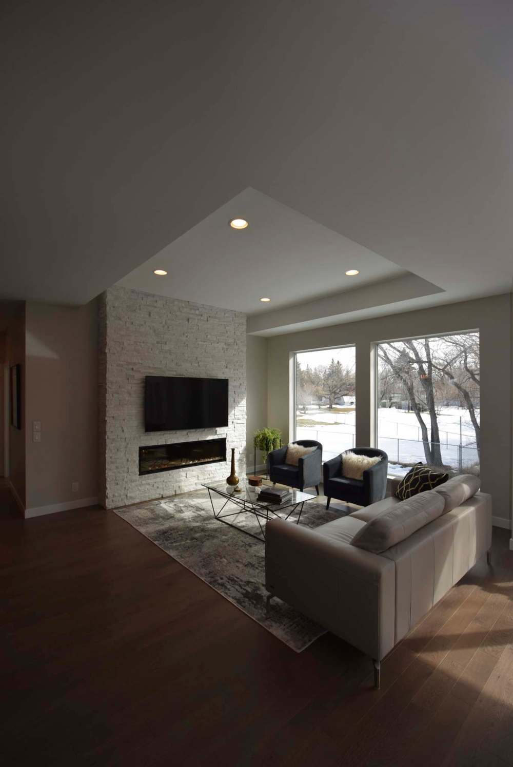 The home’s elegant living room is an inviting space that features a smashing tray ceiling, cultured stone fireplace and dual picture windows.