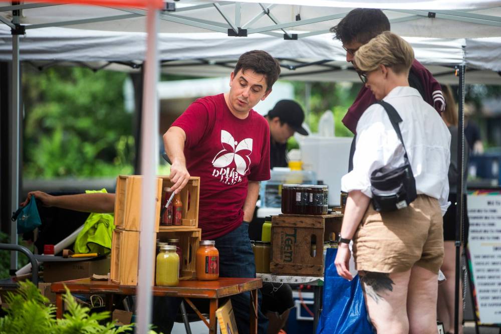 MIKAELA MACKENZIE / WINNIPEG FREE PRESS
Patrick Michalyshyn, owner of 1882 Hot Sauce, chats with customers at the Wolseley Farmers Market.