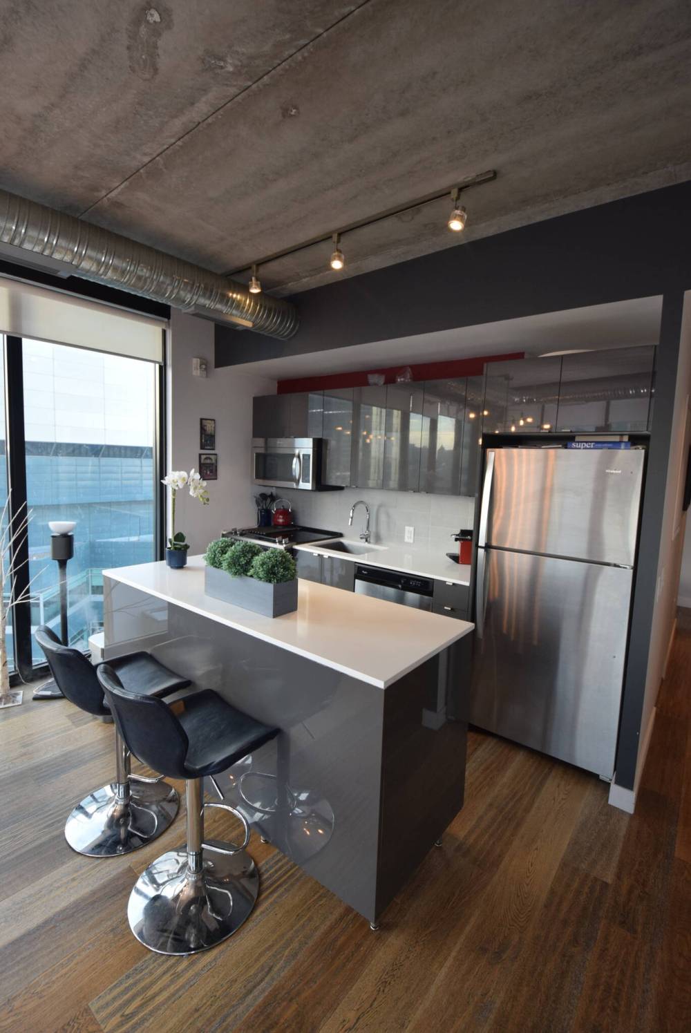 Glossy grey cabinets, white quartz countertops and a mid-sized island that seats two endow the kitchen with loads of modern style and function.