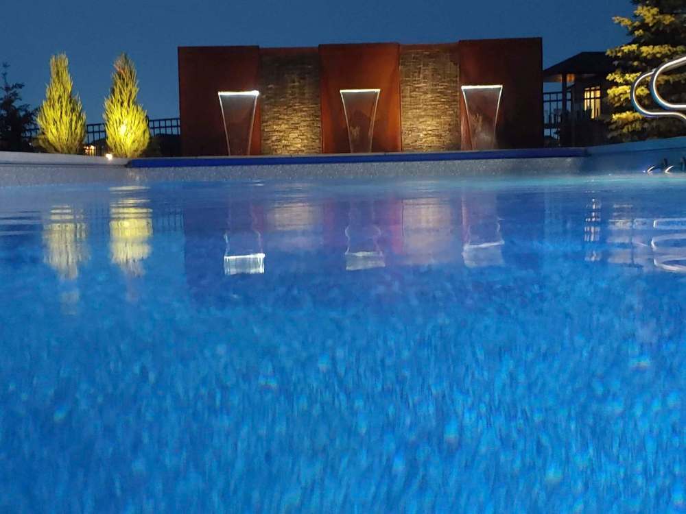 Backyard swimming pools are more popular than ever. Here the focal point is a Corten steel water feature with lights.