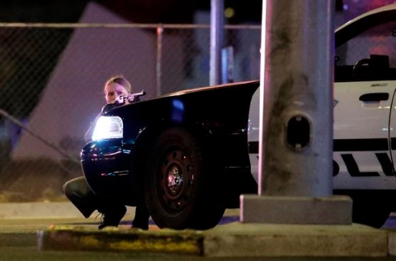 John Locher / The Associated PressA police officer takes cover behind a police vehicle during a shooting near the Mandalay Bay resort and casino on the Las Vegas Strip, Sunday.