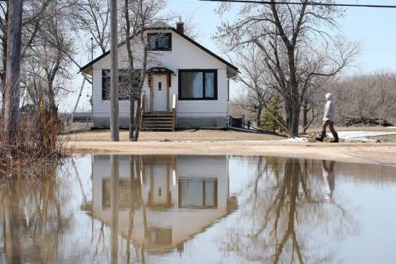A house in Transcona is reflected in a flooded roadway on Wednesday. (Shannon VanRaes / Winnipeg Free Press)
