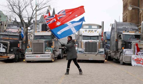 CPNathan (Jacko) Jack, an Australian living in Toronto, waves flags in front of trucks parked by Parliament Hill on Monday. (Patrick Doyle / The Canadian Press)