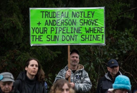 Darryl Dyck / THE CANADIAN PRESSA man holds a sign while listening as other protesters opposed to the Kinder Morgan Trans Mountain pipeline extension defy a court order and block an entrance to the company's property, in Burnaby, B.C.