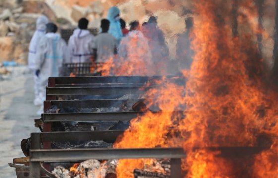 CPFamily members perform last rites for a person who died of COVID-19 as funeral pyres of other victims burn on the outskirts of Bengaluru, India. (Aijaz Rahi / The Associated Press)