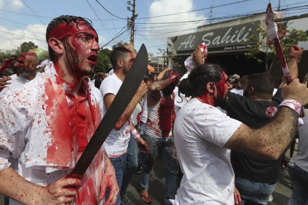 EDS NOTE: GRAPHIC CONTENT - Lebanese Shiite men bleed from self-inflicted head wounds, as they strike their heads with swords to show their grief during the Muslim Shiite holy day of Ashoura, in the southern market town of Nabatiyeh, Lebanon, Tuesday, Aug. 9, 2022. Ashoura is the annual Shiite Muslim commemoration marking the death of Imam Hussein, the grandson of the Prophet Muhammad, at the Battle of Karbala in present-day Iraq in the 7th century. (AP Photo/Mohammed Zaatari)