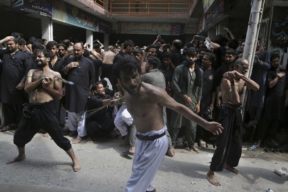 Shiite Muslims flagellate themselves with knifes on chains during a procession to mark Ashoura, in Peshawar, Pakistan, Tuesday, Aug. 9, 2022. Ashoura falls on the 10th day of Muharram, the first month of the Islamic calendar, when Shiites mark the death of Hussein, the grandson of the Prophet Muhammad, at the Battle of Karbala in present-day Iraq in the 7th century. (AP Photo/Muhammad Sajjad)