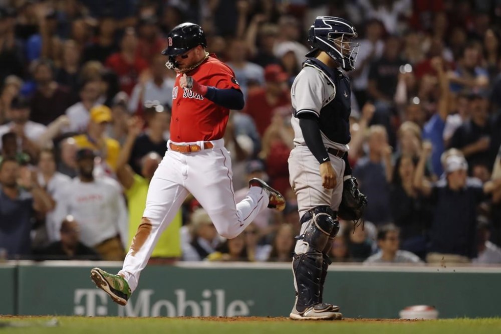 Boston Red Sox's Alex Verdugo, left, scores next to New York Yankees' Jose Trevino on a single by J.D. Martinez during the fourth inning of a baseball game Friday, Aug. 12, 2022, in Boston. (AP Photo/Michael Dwyer)
