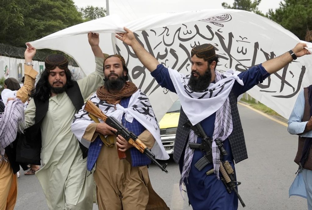 Taliban fighters hold their flag as they celebrate one year since they seized the Afghan capital, Kabul, in front of the U.S. Embassy in Kabul, Afghanistan, Monday, Aug. 15, 2022. The Taliban marked the first-year anniversary of their takeover after the country's western-backed government fled and the Afghan military crumbled in the face of the insurgents' advance. (AP Photo/Ebrahim Noroozi)