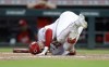 Cincinnati Reds' Jake Fraley falls to the ground after a foul ball hit him on the leg during the fifth inning of the team's baseball game against the Philadelphia Phillies in Cincinnati on Tuesday, Aug. 16, 2022. (AP Photo/Paul Vernon)