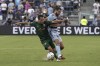 Sporting Kansas City midfielder Graham Zusi, right, and Portland Timbers midfielder Sebastián Blanco battle for the ball during the first half of an MLS soccer match Sunday, Aug. 21, 2022, in Kansas City, Kan. (AP Photo/Charlie Riedel)