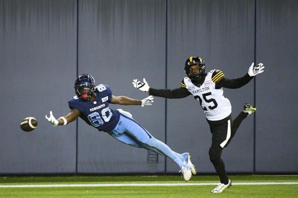 Toronto Argonauts wide receiver DaVaris Daniels (80) attempts to make the catch while Hamilton Tiger-Cats defensive back Jumal Rolle (25) defends during first half CFL football action in Toronto, on Friday, August 26, 2022. THE CANADIAN PRESS/Christopher Katsarov