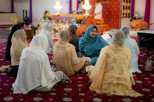 The faithful pray before the thakt, or throne, where the Guru Granth Sahib, the Sikh holy book, resides during prayer hours at the Guru Nanak Darbar of Long Island, a Sikh gurdwara, Wednesday, Aug. 24, 2022, in Hicksville, N.Y. An Afghan Sikh family of 13 has found refuge in the diaspora community on Long Island where the Sikh community is helping family members obtain work permits, housing, healthcare and find schools for the children. (AP Photo/John Minchillo)