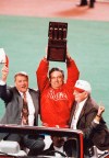 FILE - Philadelphia Phillies manager Jim Fregosi, center, holds up the NL Championship trophy as Phillies general manager Lee Thomas, left, and Phillies President Bill Giles look on during their drive around the field after the Phillies 6-3 win over the Atlanta Braves in Game 6 of the NL Playoffs, Oct. 14, 1993, Philadelphia, Pa. Lee Thomas, an All-Star player who eventually became the architect of the 1993 National League champion Philadelphia Phillies, has died. He was 86. Thomas died Wednesday, Aug. 31, 2022, at his home in St. Louis, the Phillies announced.(AP Photo/George Widman, File)