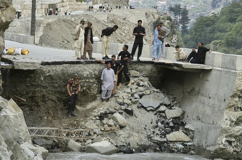 Local residents and police stand in the damaged road destroyed by floodwaters in Kalam Valley in northern Pakistan, Sunday, Sept. 4, 2022. Several countries have flown in supplies, but the Pakistani government has pleaded for even more help, faced with the enormous task of feeding and housing those affected, as well as protecting them from waterborne diseases. (AP Photo/Sherin Zada)