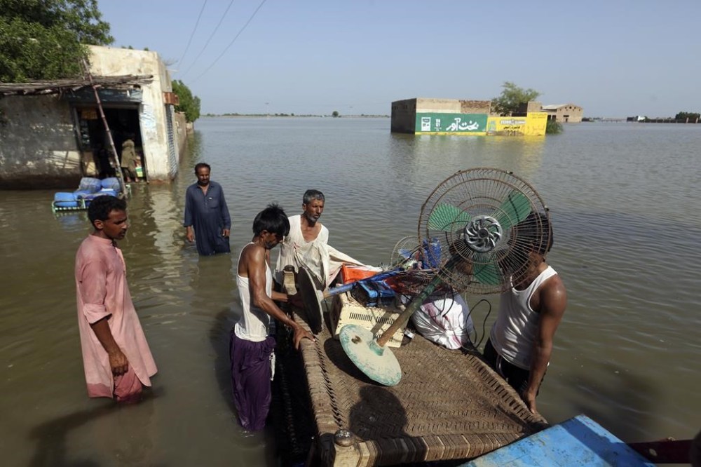 Victims of unprecedented flooding from monsoon rains use a cot to salvage belongings from their nearby flooded home, in Jaffarabad, Pakistan, Monday, Sept. 5, 2022. The U.N. refugee agency rushed in more desperately needed aid Monday to flood-stricken Pakistan as the nation's prime minister traveled to the south where rising waters of Lake Manchar pose a new threat. (AP Photo/Fareed Khan)