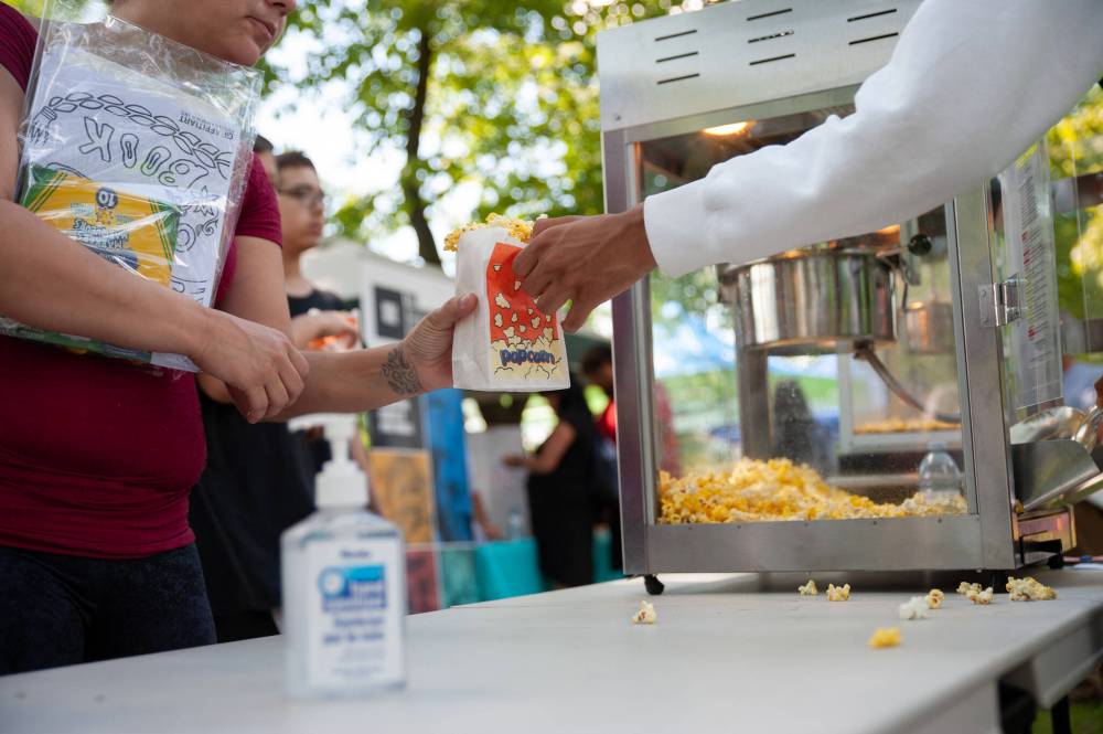 Volunteers hand out popcorn to concert attendees. (Ethan Cairns / Winnipeg Free Press)