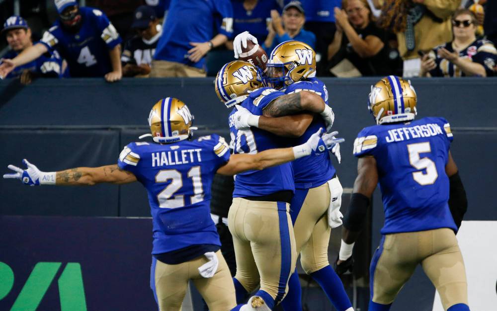 Winnipeg Blue Bombers’ Jackson Jeffcoat (94), right, celebrates his touchdown from a fumble recovery against the Calgary Stampeders during the second half CFL action in Winnipeg Thursday, August 25, 2022. The play was called back for roughing the passer. THE CANADIAN PRESS/John Woods