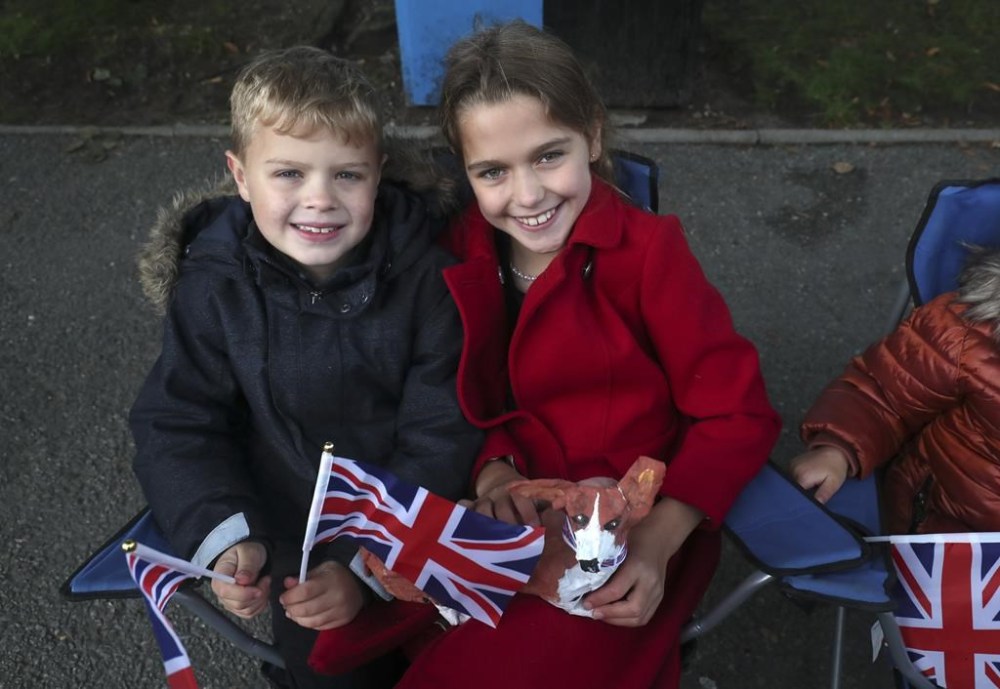 Young children wait in Ballater, Scotland ahead of the hearse carrying the coffin of Queen Elizabeth II before it passes through to make its journey to Edinburgh from Balmoral in Scotland, Sunday, Sept. 11, 2022. The Queen's coffin will be transported Sunday on a journey from Balmoral to the Palace of Holyroodhouse in Edinburgh, where it will lie at rest before being moved to London later in the week. (AP Photo/Scott Heppell)