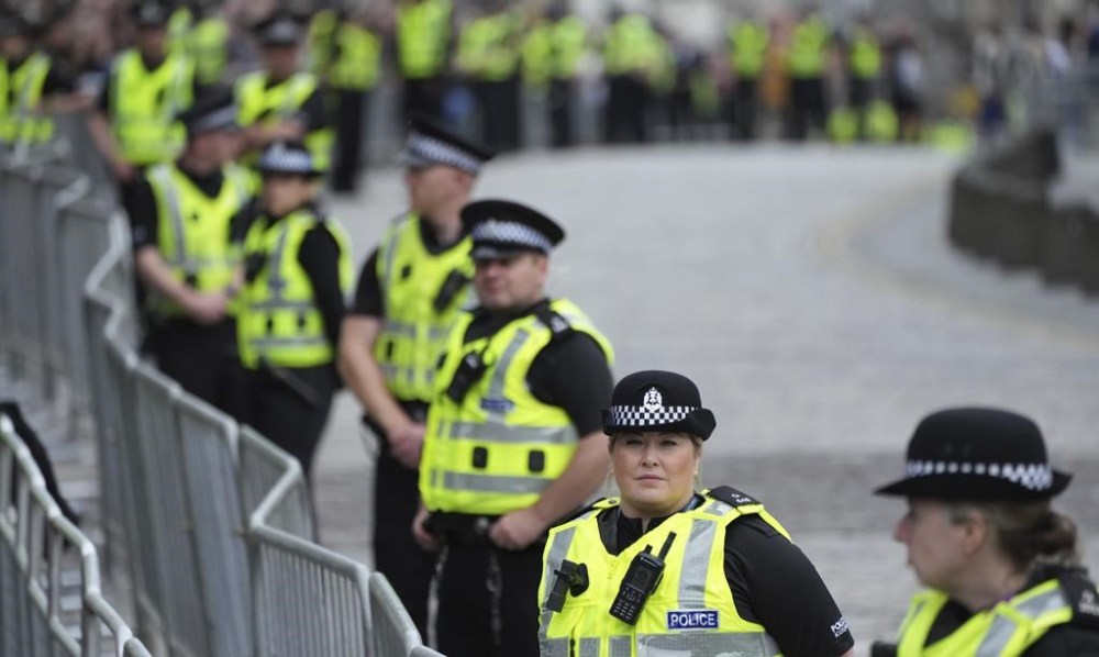 Police line the route prior to the arrival of the Queens cortege with the hearse containing her coffin on the Royal Mile in Edinburgh, Scotland, Sunday, Sept. 11, 2022. The coffin of the late Queen Elizabeth II is being transported Sunday on a journey from Balmoral to the Palace of Holyroodhouse in Edinburgh, where it will lie at rest before being moved to London later in the week. (AP Photo/Jon Super)