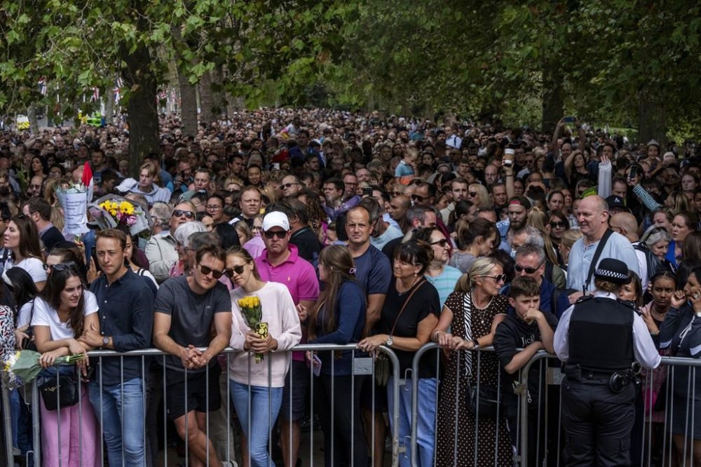 People wait in line to lay flowers for Queen Elizabeth II in front of Buckingham Palace, in London, Sunday, Sept. 11, 2022. (AP Photo/Nariman El-Mofty)