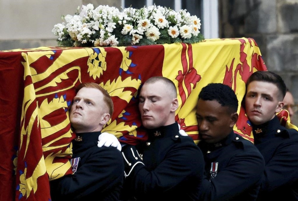 Pallbearers carry the coffin of Queen Elizabeth II, draped with the Royal Standard of Scotland, as it arrives at Holyroodhouse, where it will lie in rest for a day, in Edinburgh, Sunday, Sept. 11, 2022. Queen Elizabeth II, Britain's longest-reigning monarch and a rock of stability across much of a turbulent century, died Thursday Sept. 8, 2022, after 70 years on the throne. She was 96. (Alkis Konstantinidis/Pool Photo via AP)