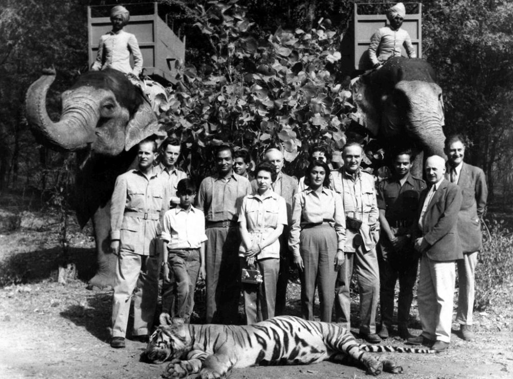FILE- Britain's Queen Elizabeth II and Prince Philip, stand with their hosts Maharajah and Maharanee of Jaipur, in the forests of Rajasthan, India, Jan. 24, 1961. From left; Prince Philip, unknown, unknown child, Maharajah of Jaipur, Queen, Maharanee Gayatri Devi, rest are unamed. The tiger in the foreground was shot by Prince Philip and the elephants used in the hunt are seen at the back. The queen’s death provoked sympathies from some while for a few others, it jogged memories of a bloody history under the British crown. (AP Photo)