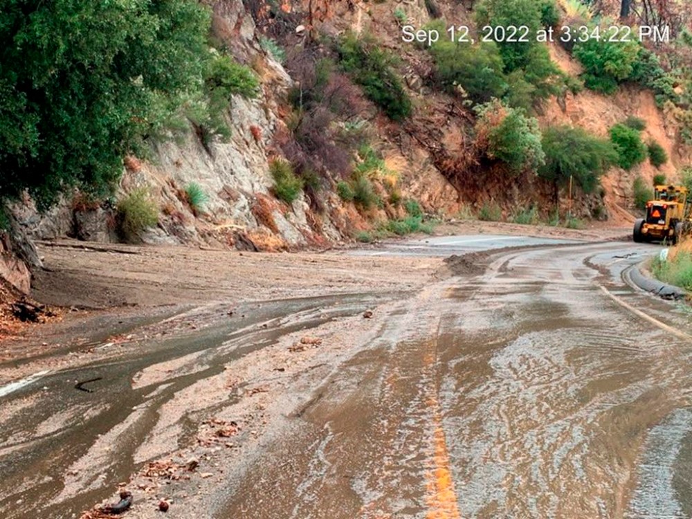 This Monday afternoon, Sept. 12, 2022, image released by Caltrans District 8 shows maintenance crews on scene cleaning debris from mudslides that closed part of Highway SR-38 in the San Bernardino Mountains, Calif. The mud flows and flash flooding occurred in parts of the San Bernardino Mountains where there are burn scars, areas where there's little vegetation to hold the soil, from the 2020 wildfires. (Caltrans District 8 via AP)