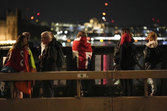 A woman draped with a Union flag waits with other people in the queue near Westminster Palace. (Markus Schreiber / The Associated Press)