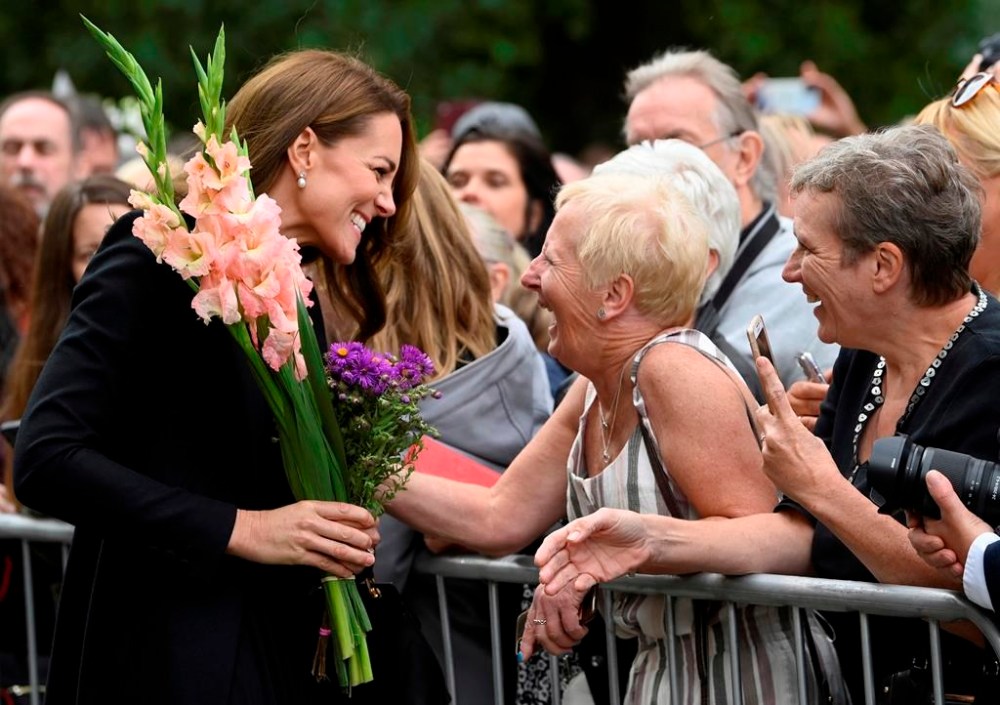 Kate, Princess of Wales reacts with a well-wisher as she and Prince William, view floral tributes left by members of the public, in memory of late Queen Elizabeth II, at the Sandringham Estate, in Norfolk, England, Thursday, Sept. 15, 2022. Queen Elizabeth II, Britain's longest-reigning monarch died Thursday Sept. 8, 2022, after 70 years on the throne. (Toby Melville/Pool via AP)
