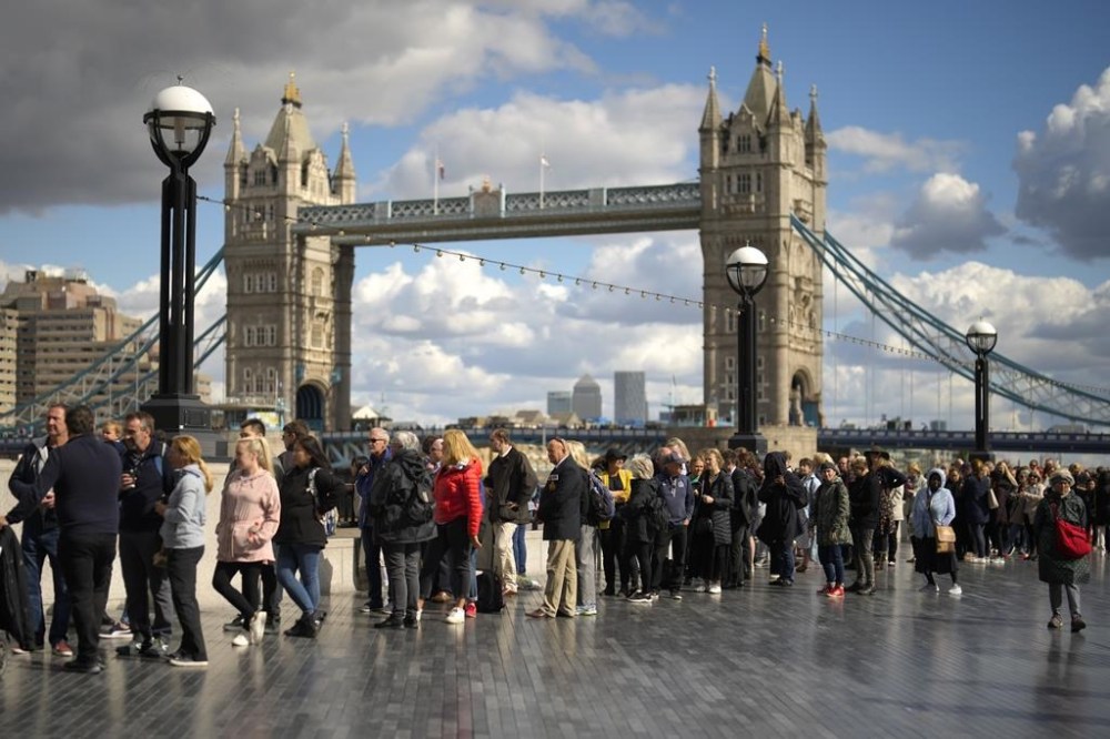 People walk in a queue in front of Tower Bridge to pay their respects to the late Queen Elizabeth II during the Lying-in State at Westminster Hall, in London, England, Friday, Sept. 16, 2022. The Queen will lie in state in Westminster Hall for four full days before her funeral on Monday Sept. 19. (AP Photo/Markus Schreiber)