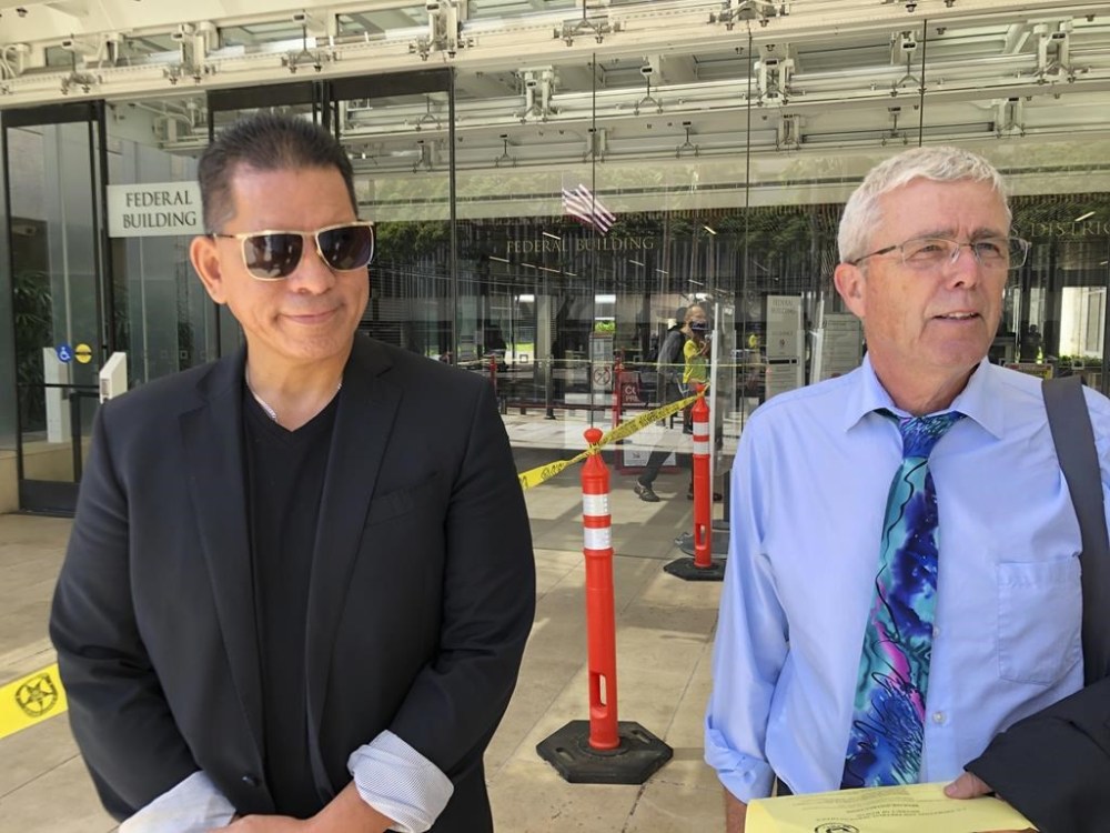 Stewart Olani Stant, left, listens as his attorney Cary Virtue speaks to reporters outside U.S. District Court in Honolulu, on Monday, Sept. 19, 2022. Stant, a former Maui County official, and Milton Choy, the owner and manager of the wastewater company H2O Process Systems LLC, each pleaded guilty Monday for a scheme in which Choy paid Stant $2 million in bribes in exchange for more than $19 million in wastewater contracts. (AP Photo/Audrey McAvoy)