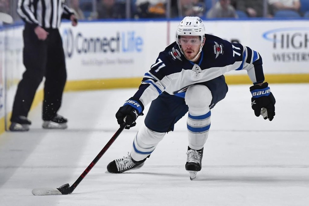 FILE - Then-Winnipeg Jets left wing Evgeny Svechnikov, of Russia, reaches for the puck during the first period of an NHL hockey game against the Buffalo Sabres in Buffalo, N.Y., Wednesday, March 30, 2022. Evgeny Svechnikov now plays for the San Jose Sharks. The Czech Foreign Ministry told two NHL teams opening the season in Prague that any Russian players would not be welcome because of the war in Ukraine, prompting league officials to downplay the impact of the attempted ban. The Nashville Predators and San Jose Sharks are to play regular season games on Oct. 7 and 8 at Prague’s O2 Arena. (AP Photo/Adrian Kraus, File)