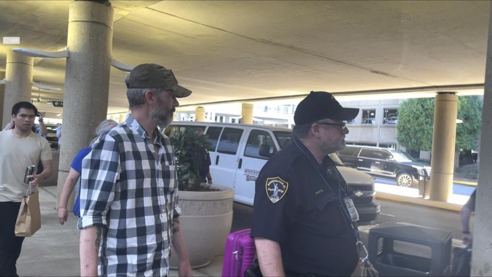 Andy Huynh, far left, and Alex Drueke, right, are seen leaving Birmingham-Shuttlesworth International Airport in Birmingham, Ala., Saturday, Sept. 24, 2022. The U.S. military veterans disappeared three months ago while fighting Russia with Ukrainian forces. They were released earlier this week by Russian-backed separatists as part of a prisoner exchange. (AP Photo/Kim Chandler)