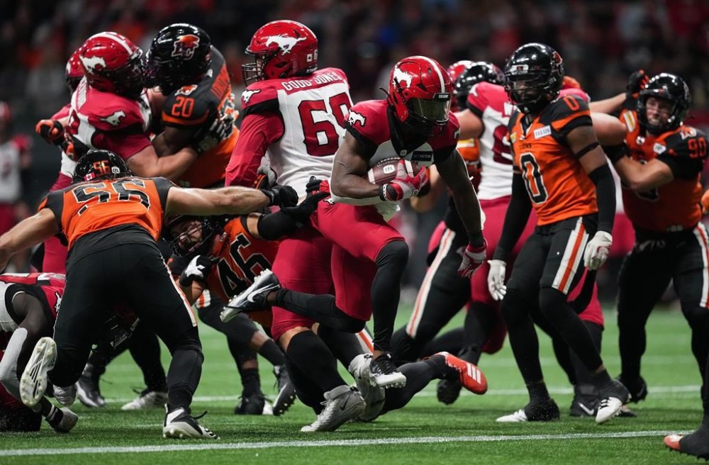 Calgary Stampeders' Ka'Deem Carey, centre, runs past B.C. Lions' David Menard (56) and Ben Hladik (46) to score a touchdown during the first half of CFL football game in Vancouver, on Saturday, Sept. 24, 2022. THE CANADIAN PRESS/Darryl Dyck