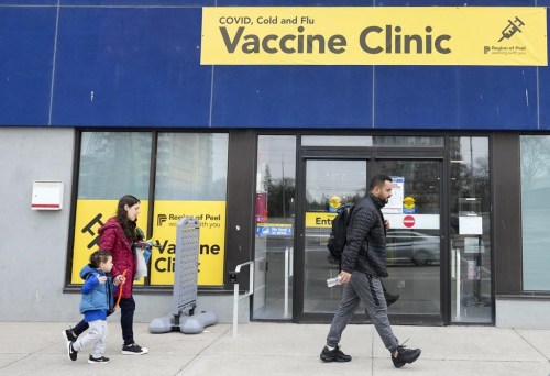 People walk past a vaccine clinic during the COVID-19 pandemic in Mississauga, Ont., on Wednesday, April 13, 2022. THE CANADIAN PRESS/Nathan Denette