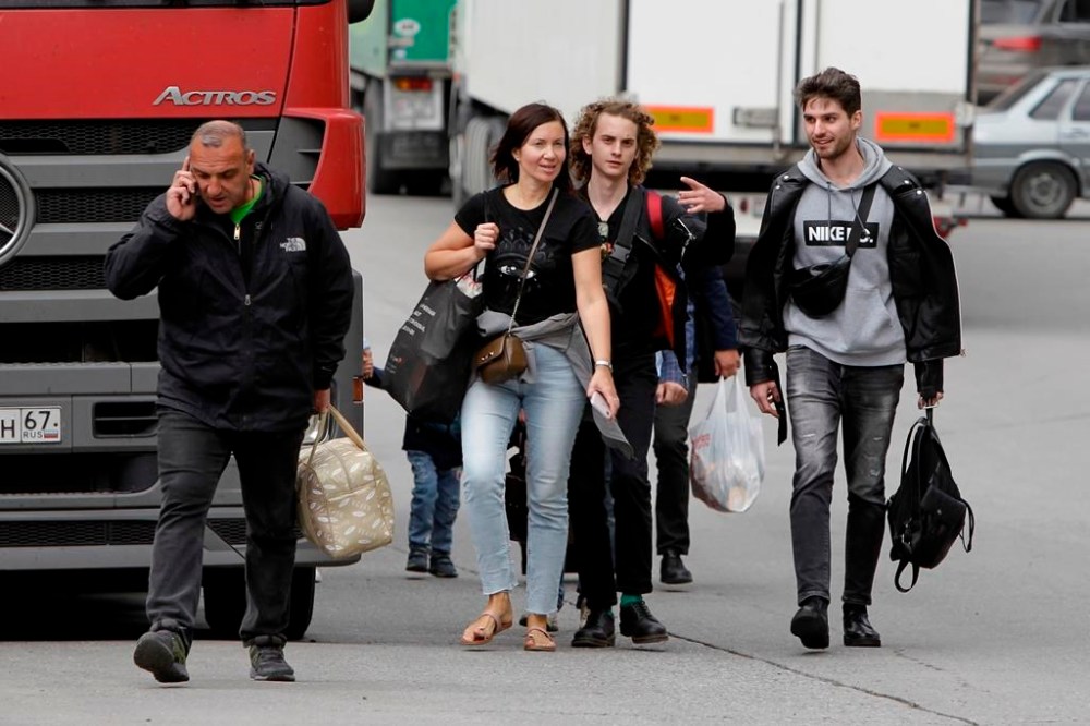 FILE A group of young Russians walk after they crossed the border crossing Verkhny Lars between Georgia and Russia on Friday, Sept. 23, 2022. Long lines of vehicles have formed at a border crossing between Russia's North Ossetia region and Georgia after Moscow announced a partial military mobilization. A day after President Vladimir Putin ordered a partial mobilization to bolster his troops in Ukraine, many Russians are leaving their homes. (AP Photo/Shakh Aivazov, File)